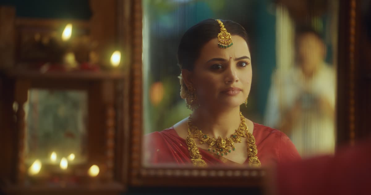 A woman in gold jewellery seen in an ornate mirror
