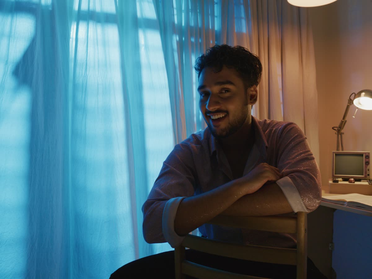 A young man smiles in blue window light