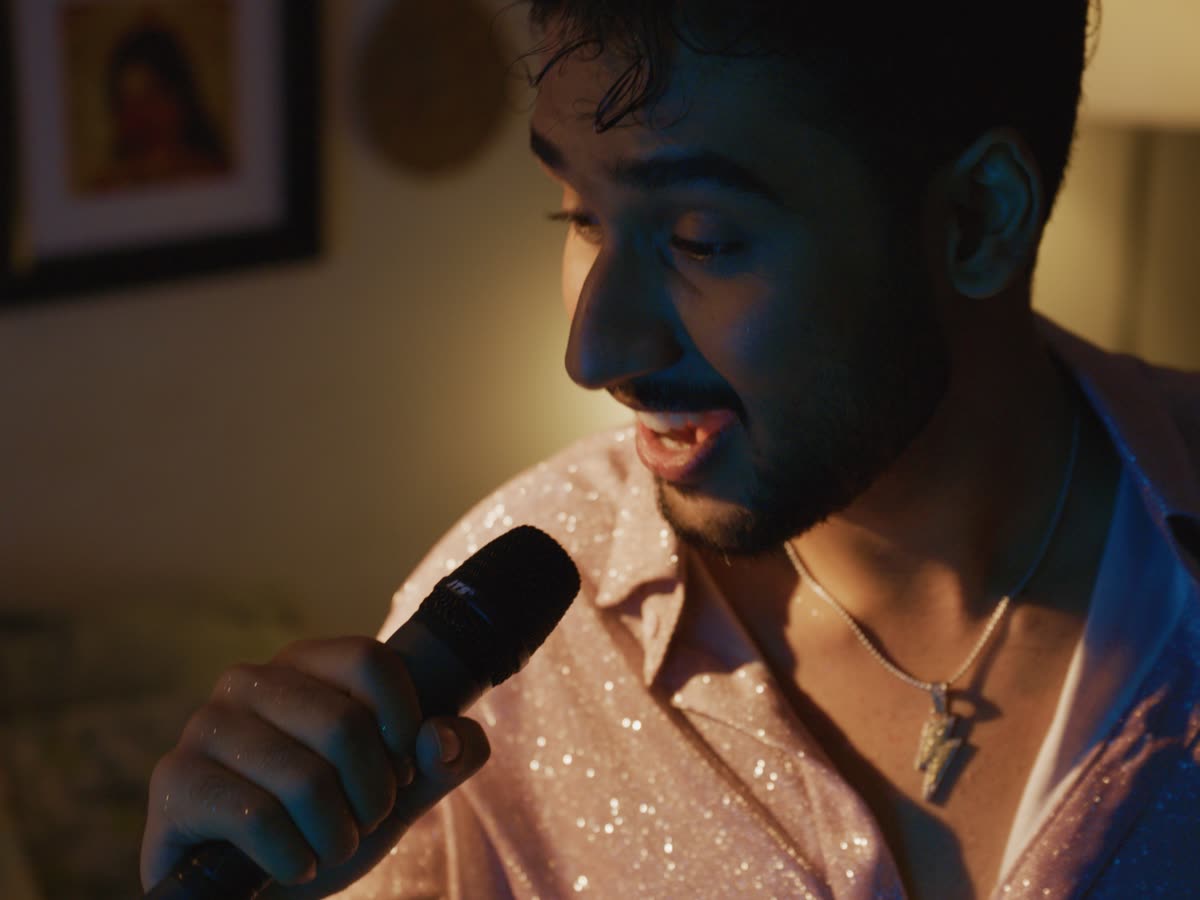 A singer in a sequinned shirt holds a microphone