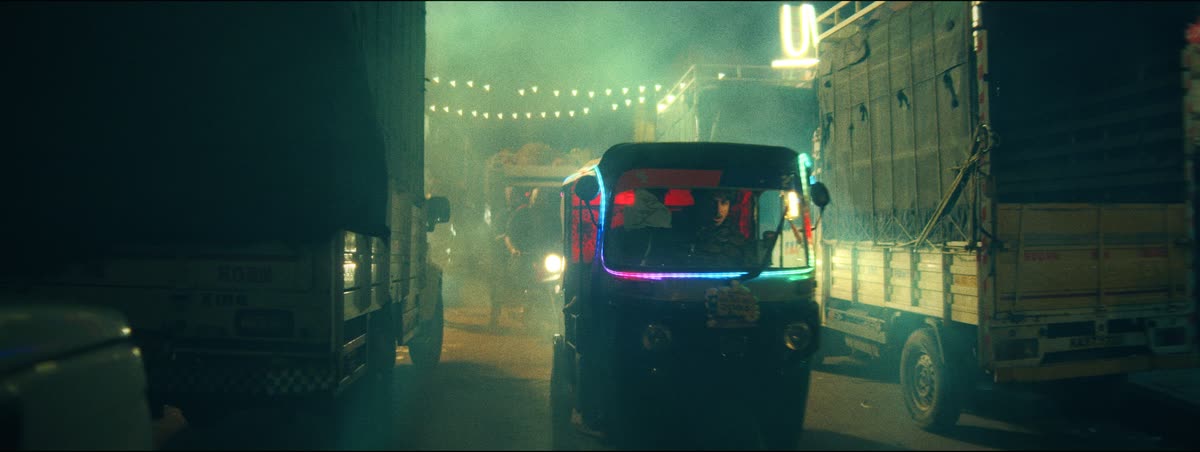 An auto-rickshaw glows through green haze in a narrow lane